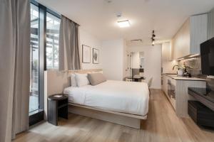 a bedroom with a white bed and a kitchen at Smithe House in Vancouver