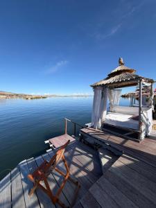 a wooden dock with a gazebo and a chair on the water at Uros Lake Titicaca Lodge in Puno
