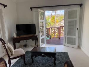 a living room with a television and a table at Charming poolside condo in Cap Cove in Cap Estate