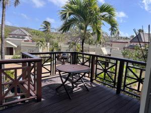 a wooden balcony with a table and a palm tree at Charming poolside condo in Cap Cove in Cap Estate