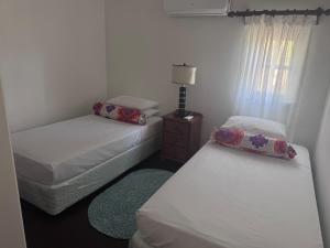 a room with two beds and a table with a lamp at Charming poolside condo in Cap Cove in Cap Estate +6 photos