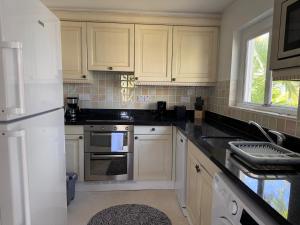 a kitchen with white cabinets and black counter tops at Charming poolside condo in Cap Cove in Cap Estate