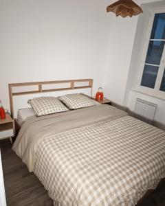 a bedroom with a bed with a checkered blanket at L'immeuble du Monde Rose - Appartements neufs climatisés - classés 3 étoiles - Vic le Comte - Auvergne in Vic-le-Comte
