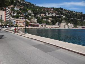 a street next to a body of water with a mountain at Les pieds dans la mer Best place in Villefranche-sur-Mer