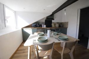 a kitchen with a wooden table with chairs and a tableasteryasteryasteryasteryastery at Le Perchoir Charm and light in Pau