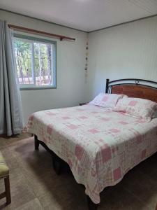 a bedroom with a bed with a quilt on it at Cabaña el Encanto in Villarrica