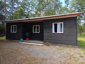 a small black house with a porch in a yard at Cabaña el Encanto in Villarrica