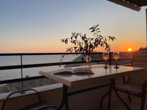 a table with two glasses and a book on a balcony at Glyfada Seaview Home 126 by New Era in Glyfada