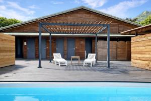 a deck with two chairs and a table next to a pool at POOL AC King Bed Cozy Rooms - Villa Vaiaire in Vaïare