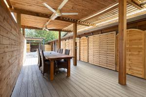 a wooden table on a deck with a ceiling fan at POOL AC King Bed Cozy Rooms - Villa Vaiaire in Vaïare