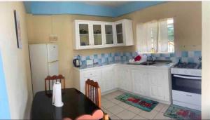 a kitchen with white cabinets and a black table with chairs at Duncan Apartment #1 in Port Elizabeth