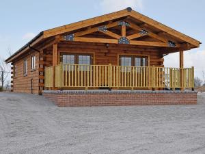 a log cabin with a porch and a fence at No 6 Lake View Lodges - 28283 in Old Leake