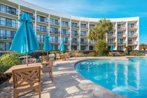 a hotel with a pool and chairs and umbrellas at Pirates Bay B114 in Fort Walton Beach
