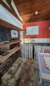 a kitchen with white cabinets and a red wall at Pousada Estalagem Mirante in Aiuruoca