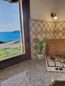a kitchen with a stove and a window with the ocean at Casa Lugori in Torre Dei Corsari
