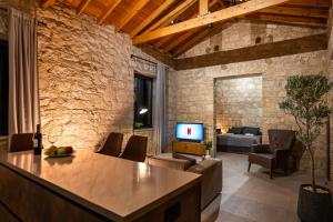 a living room with a table and a couch and a tv at Philoxenia Stone Suites in Choulou
