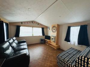 a living room with a couch and a bed and window at Miranda and Pauls Caravan in Leysdown-on-Sea