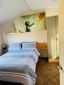 a bedroom with a bed with blue pillows and a painting at Miranda and Pauls Caravan in Leysdown-on-Sea +18 photos