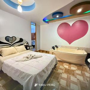 a bedroom with a bed and a bathtub with a heart on the wall at Yaku Hotel in Cajamarca