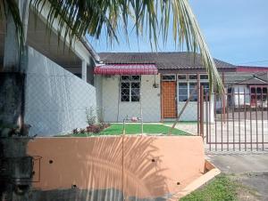 a fence in front of a house with a yard at Santai DPermai Homestay in Selama