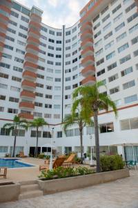 a large building with palm trees in front of it at Amplio, cómodo y cerca Del Mar in Porlamar