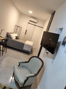 a living room with a tv and a chair and a bed at Loft 101 in Rio de Janeiro