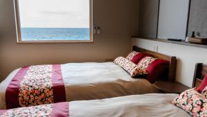 a bedroom with two beds and a window with the ocean at SAKURA YAKUSHIMA in Yakushima