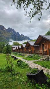 a row of lodges in a field with mountains in the background at Villas Jezerca in Valbonë