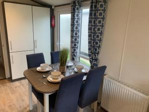 a dining room with a wooden table and blue chairs at Lily's caravan in Meliden
