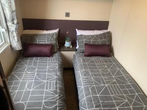 two twin beds in a small room with at Lily's caravan in Meliden