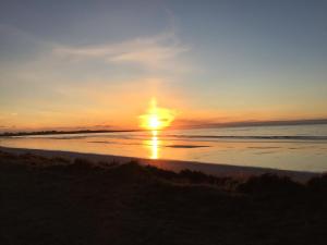 a sunset on the beach with the sun setting at Holiday Home Croft46 in Clachan