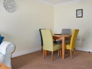 a dining room table with chairs and a clock on the wall at Dicks View in Ventnor