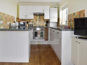 a kitchen with white cabinets and stainless steel appliances at Dicks View in Ventnor
