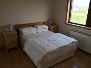 1 dormitorio con 1 cama con sábanas blancas y ventana en Holiday Home Croft46 en Clachan