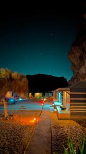 a parking lot at night with lights on a beach at Rum Arena camp in Wadi Rum +4 photos
