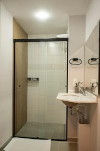 a bathroom with a glass shower and a sink at Essential 2U in São Paulo