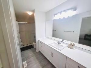 a white bathroom with a sink and a mirror at Modern 4BDRM Home-2 King Bed- Full House in Edmonton +20 photos
