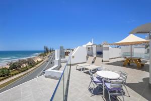 a patio with tables and chairs and the beach at Grand Palais Boolarong Beachside Apartments in Alexandra Headland