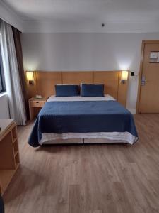 a bedroom with a bed with blue sheets and blue pillows at MN Gotado Hotel Flat Guarulhos Aeroporto in Guarulhos +37 photos