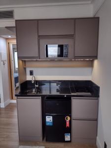 a kitchen with a sink and a microwave at MN Gotado Hotel Flat Guarulhos Aeroporto in Guarulhos