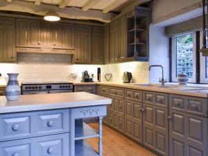 a kitchen with wooden cabinets and a sink at Barn End in Watermillock
