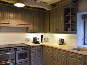 a kitchen with wooden cabinets and a stove top oven at Barn End in Watermillock