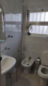 a white bathroom with a sink and a toilet at Room 3 - Music House in Conceição