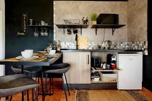 a kitchen with a table with stools and a counter at Bougainvillea House in Ponta do Pargo +25 photos