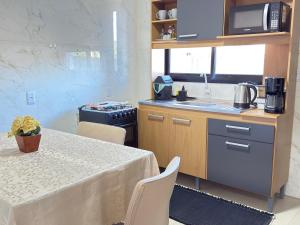 a kitchen with a table and a sink and a microwave at Sobrado NOVO próximo BR 290 in São Gabriel