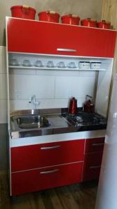 eine rote Küche mit Spüle und Herd in der Unterkunft Residencial Maia in Capão da Canoa