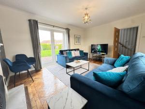 a living room with a blue couch and a tv at Very Spacious 4 Bedroom house with large garden in Leamington Spa