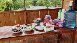 a wooden table with bowls of food and a bottle of water at War Nyampun Homestay in Waisai