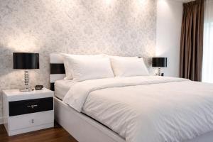a bedroom with a white bed with a nightstand and two lamps at Bougain Villa Gemanafushi in Gemanafushi