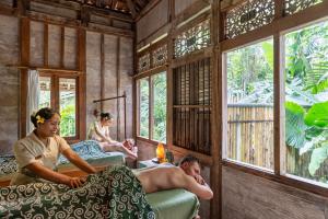 a group of people laying in beds in a room with windows at Korurua Dijiwa Ubud in Ubud